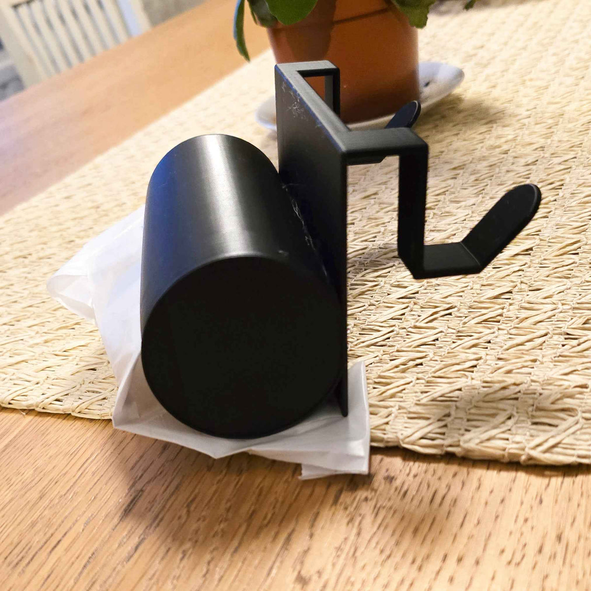 Musta jätepussiteline keittiön pöydällä, jossa roskapussi valmiiksi asetettuna. Kätevä säilytysratkaisu oviin ja laatikoihin.