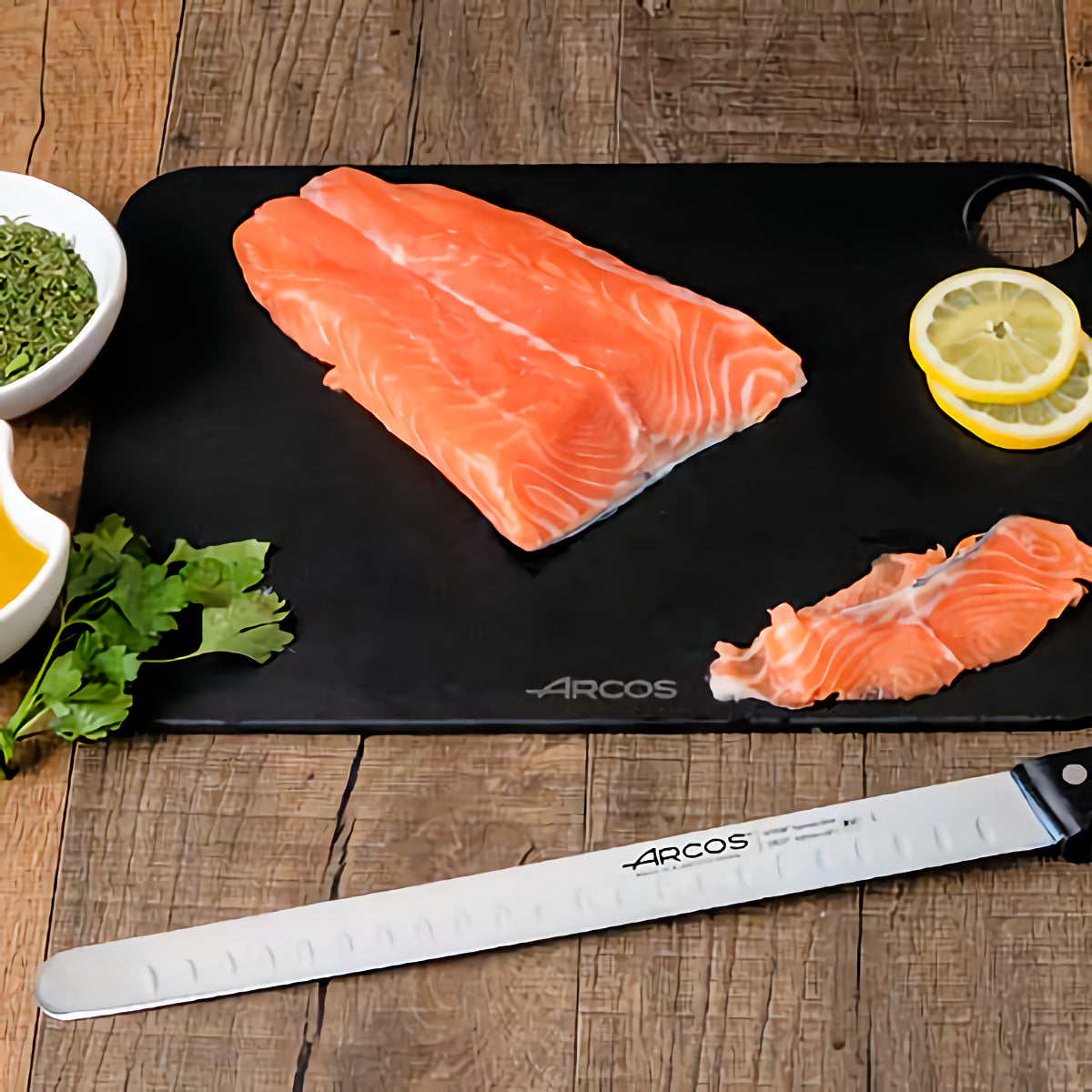Arcos lohiveitsi 30 cm leikkuulaudalla lohifileen vieressä. Ovaalihionta ja taipuisa terä takaavat tarkan leikkuun.
