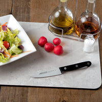 Arcos Vihannesveitsi 10 cm leikkuulaudalla vihannesten vieressä, täydellinen pilkkomiseen ja kuorintaan kotikeittiössä.