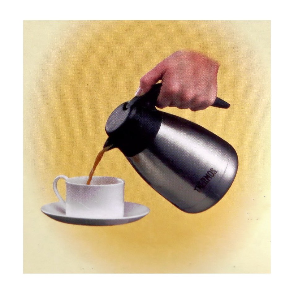 Käytössä oleva Thermospannu Brasilia TGS-600 0,6 L - Termoskaadin, josta kaadetaan kuumaa juomaa valkoiseen kuppiin.