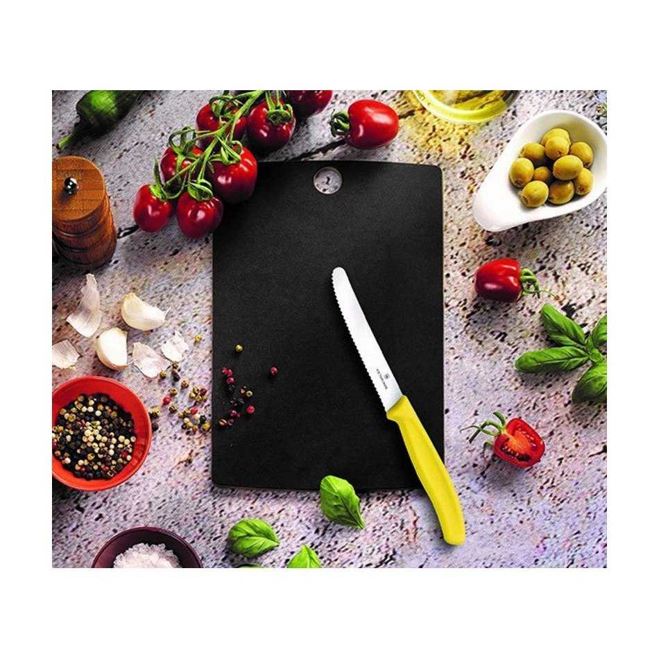 Victorinox Puukuitu Leikkuulauta S musta käytössä keittiössä, leikkuuveitsi ja tuoreita raaka-aineita leikkuulaudan ympärillä.