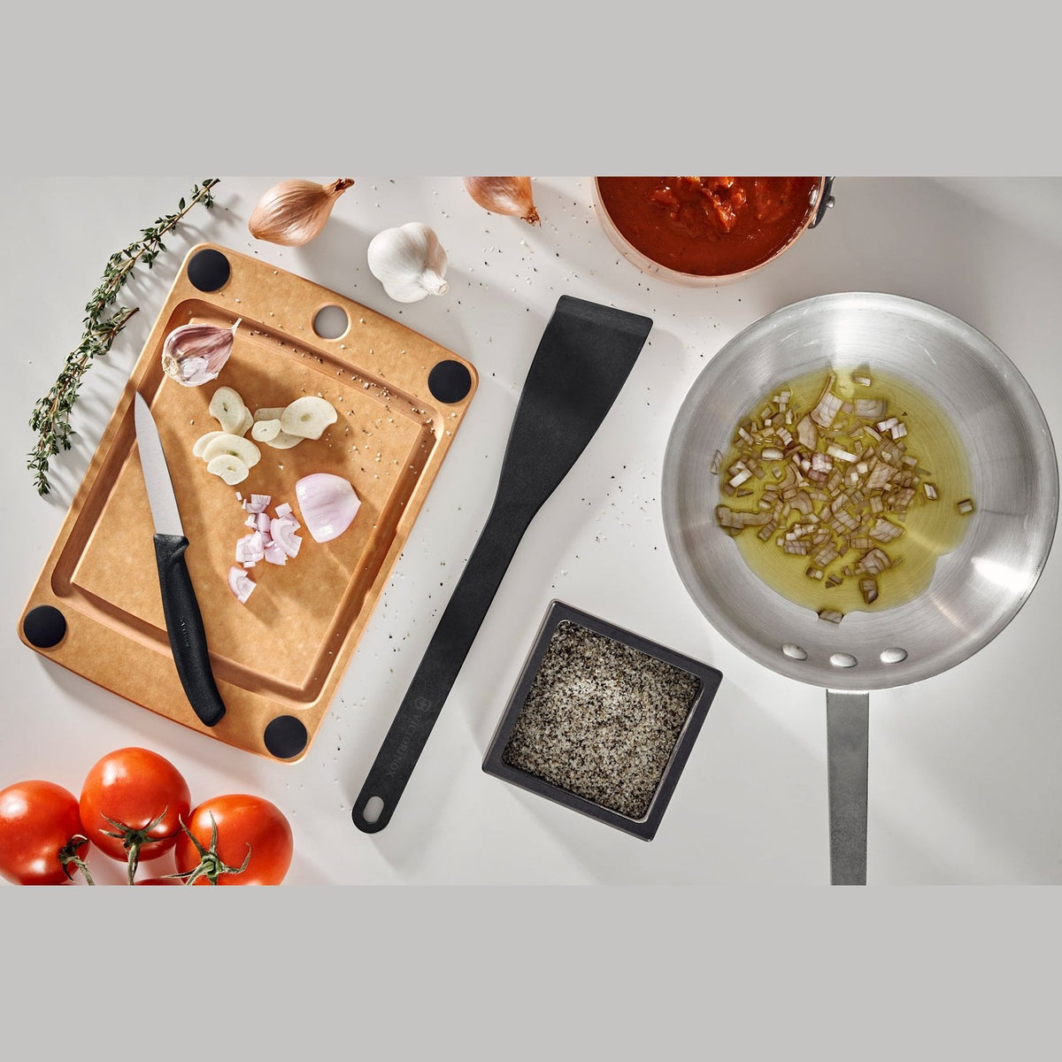 Victorinox puukuitu leikkuulauta käytössä keittiössä, leikattuja vihanneksia ja veitsi, kestävä ja käytännöllinen ruoanlaittoon.