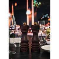 London Suolamylly ja pippurimylly ruokapöydällä, elegantti tumman ruskea muotoilu, taustalla kattaus.